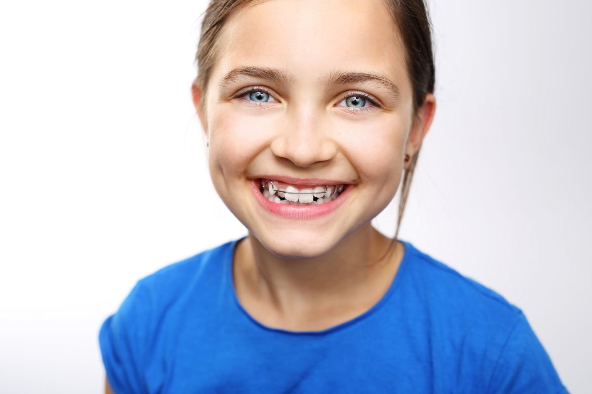 young girl smiling with braces Why Your Child Should See An Orthodontist By Age 7